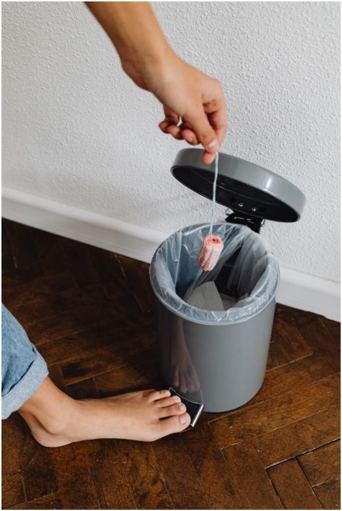 A person throwing out a tampon in a trash can. 