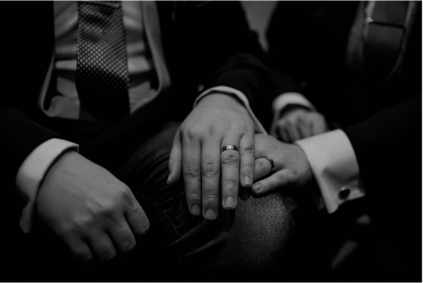 Two grooms' hands resting on on top of each other