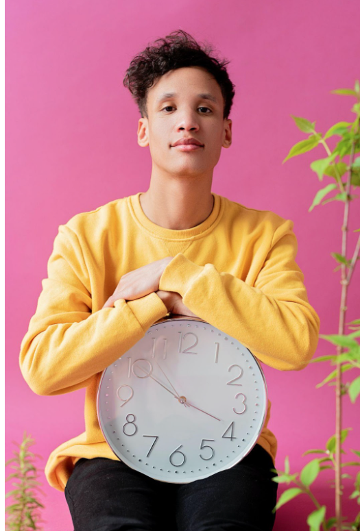 person in a yellow shirt holding a clock