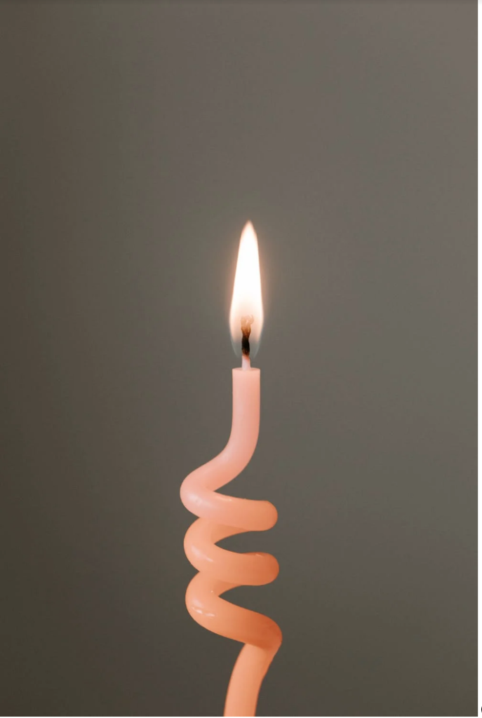 A lit peach colored spiral candle 