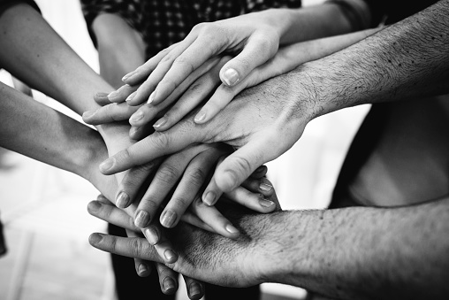many hands placed on top of each other in black and white. 
