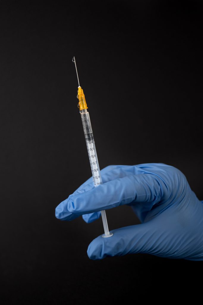 A gloved hand holding a syringe.
