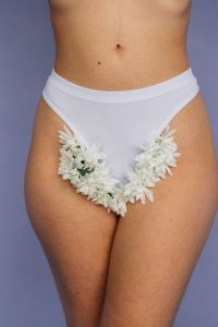 An person wearing a white underwear lined with white flowers 