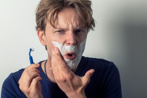 A person making an angry face while shaving 