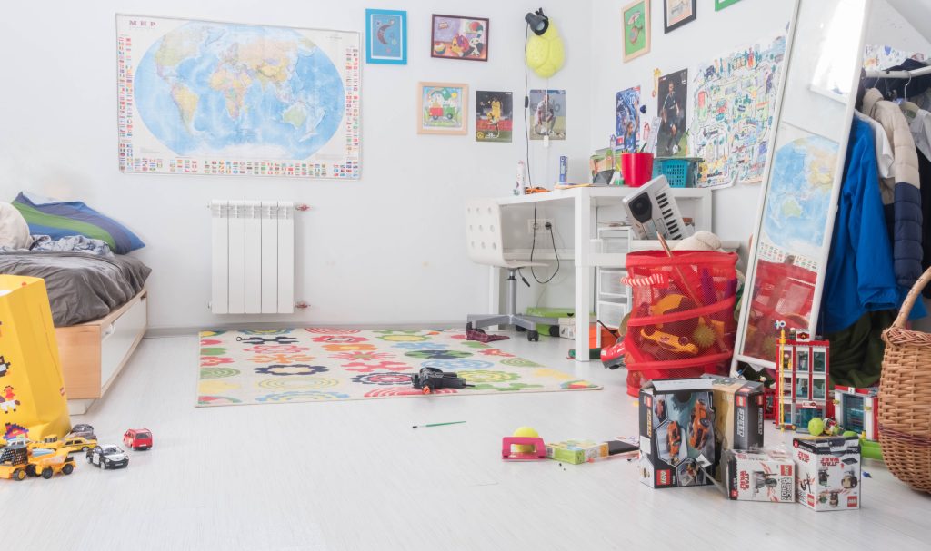 A play room with a world map on the wall, toy cars on the floor, and a rug.