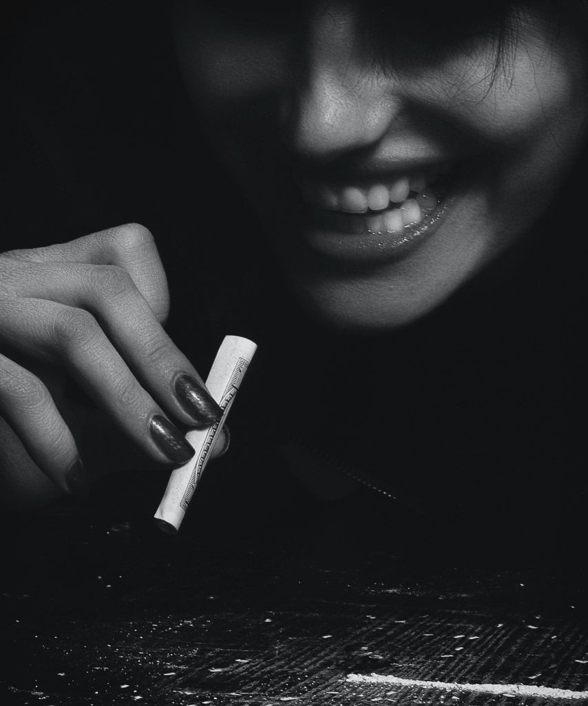 A person smiling at a line of white powder.