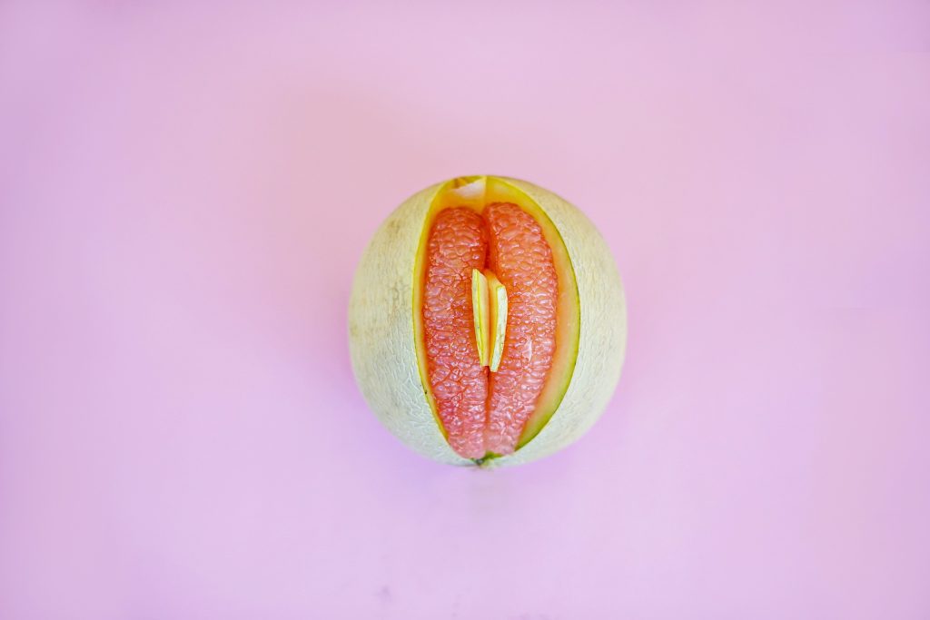 A melon partially open with slices of grapefruit. The melon resembles a vulva.
