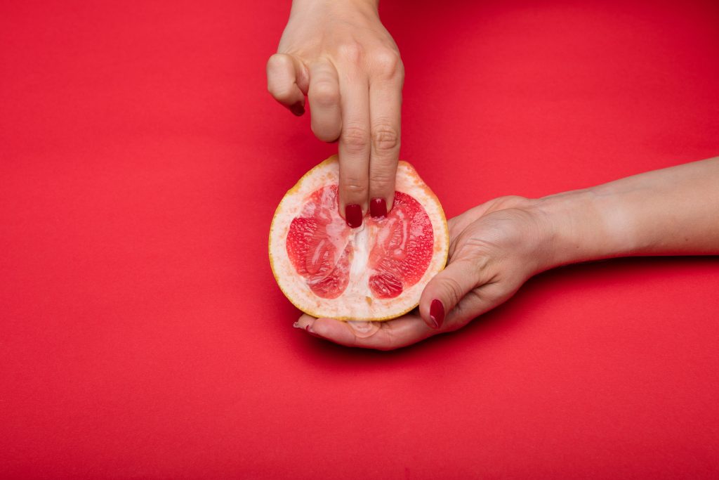 A person fingering the middle of a grapefruit.