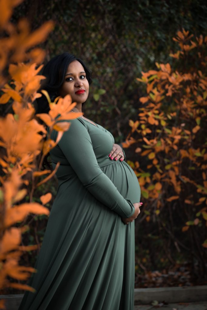 A pregnant person in a long green dress.