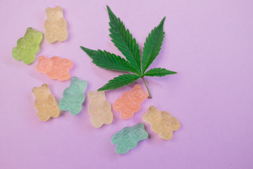 A marijuana leaf next to gummy bears.