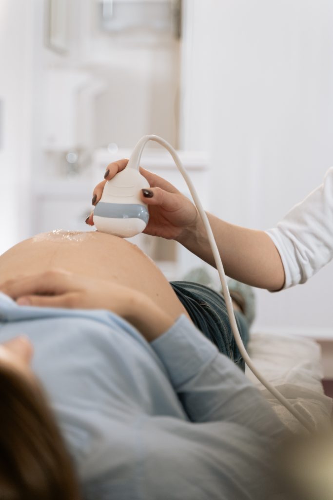 A person performing an ultrasound on a pregnant person.