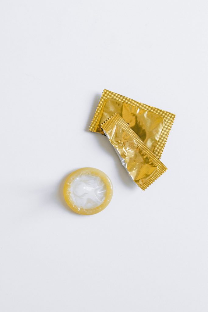 A condom next to its gold wrapper.