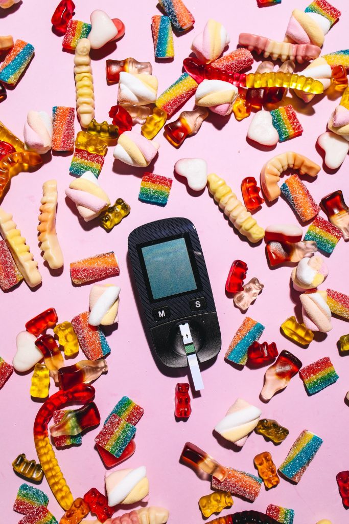 A glucose monitor surrounded by colorful candy.