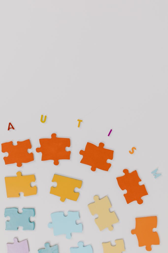 Red, orange, yellow, and blue puzzle pieces. Above the puzzle pieces "AUTISM" is spelled out.