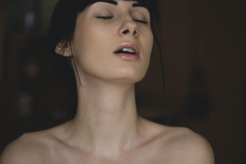 A topless person with their eyes closed and mouth partially open.
