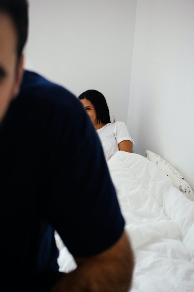 Man with woman behind him lying on bed
