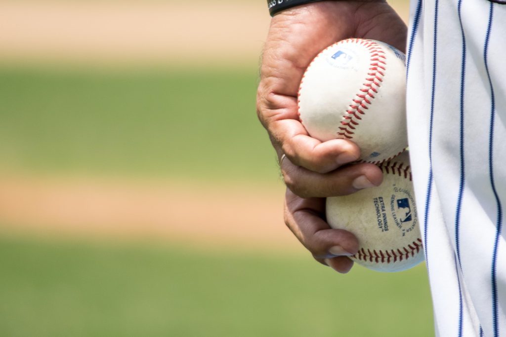 Close-up of baseball player's hand holding two baseballs right next to each other in one hand