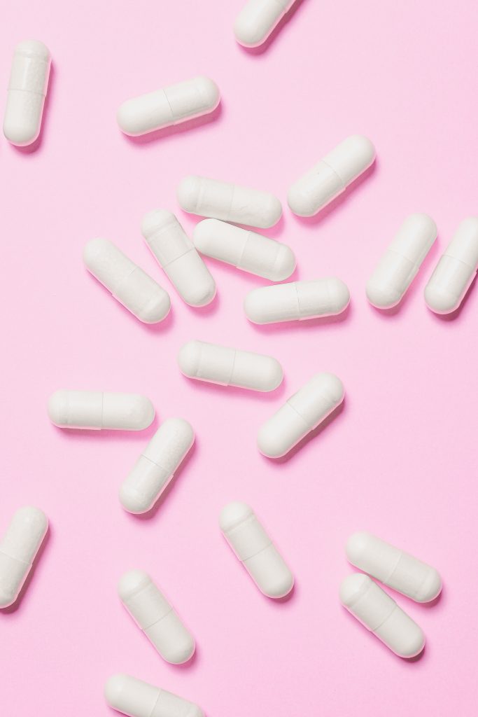 Multiple white pills against a pink background.