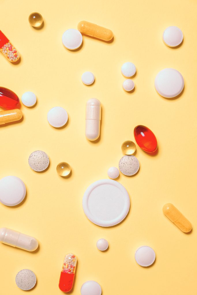 A variety of pills against a yellow background.