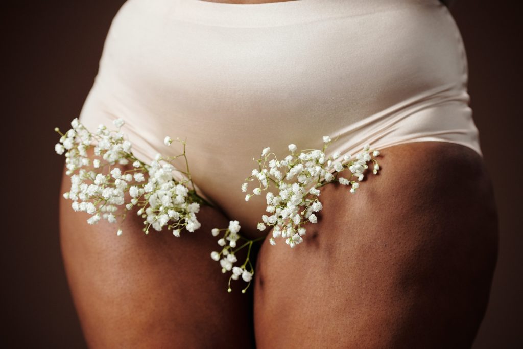 A person from the waist down wearing underwear with flowers peeking out the bottom.