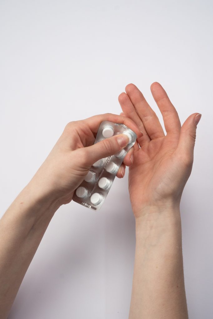 A pair of hands holding a pack of pills.