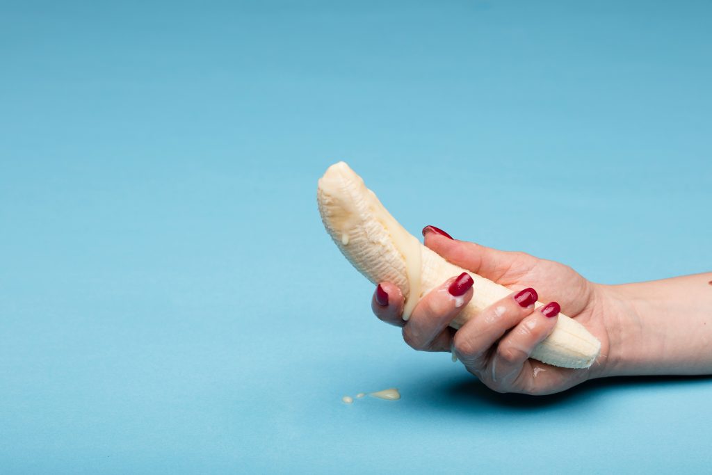 A hand holding a banana with a milky substance on it.
