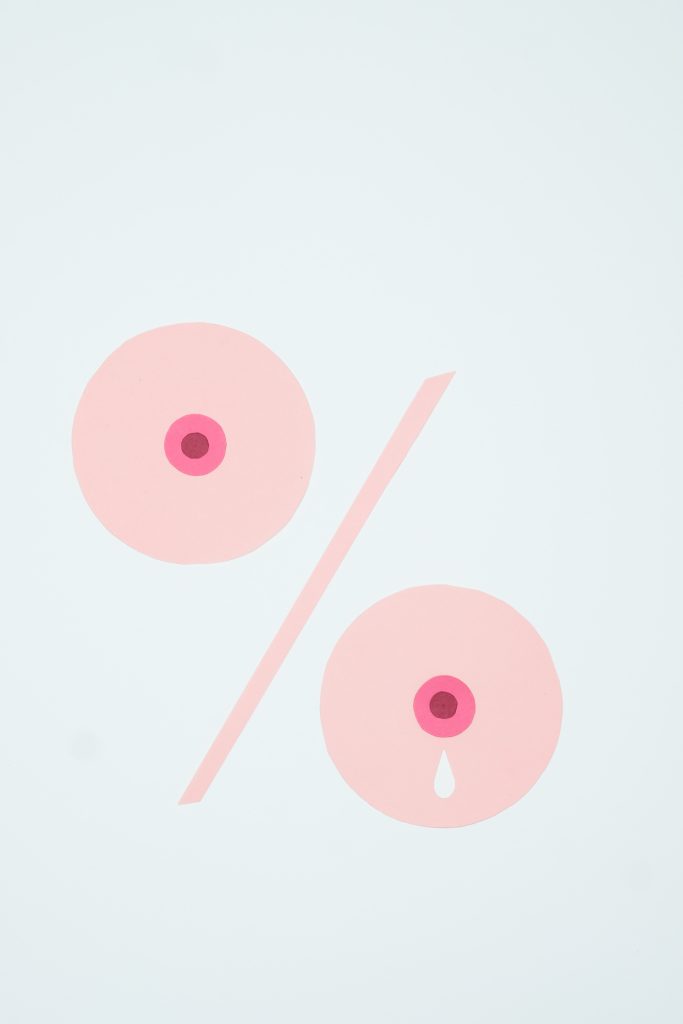 Two light pink circles with pink circle centers, that resemble breasts. There is one white droplet on the right pink circle.