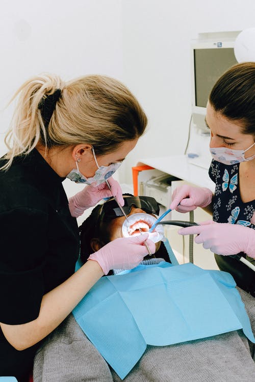 Two dentists working on a patient wearing a dental dam.