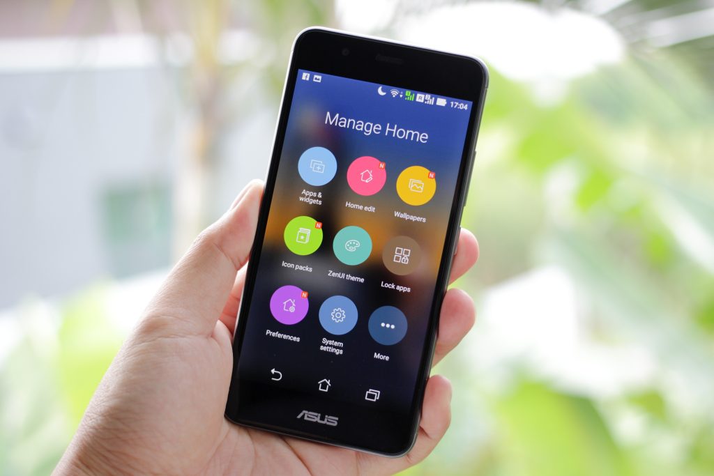A cellphone with apps on the home screen and "Manage Home" on the screen.