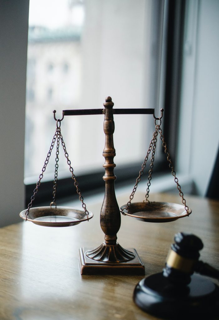 The scales of justice on a desk with a gavel in the foreground. 